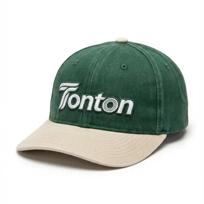 Front view of tonton custom forest green washed cotton baseball cap with a beige curved brim and white logo.